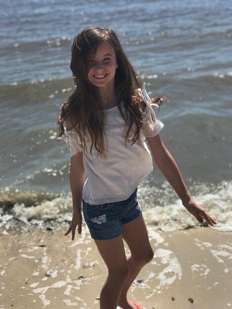 Portrait of smiling girl standing against sea at beach