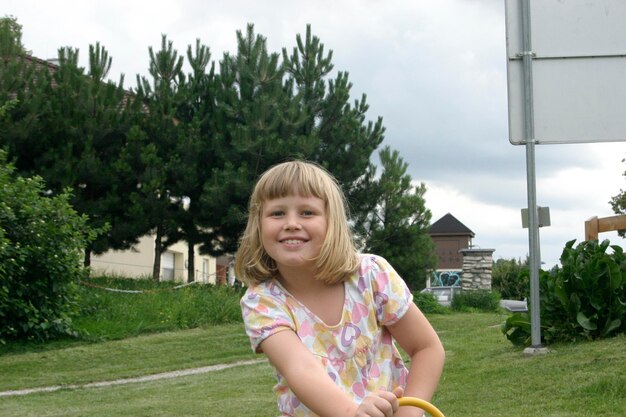 Photo portrait of smiling girl standing against trees in park