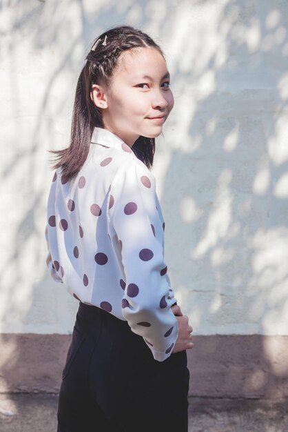 Portrait of smiling girl standing against wall outdoors