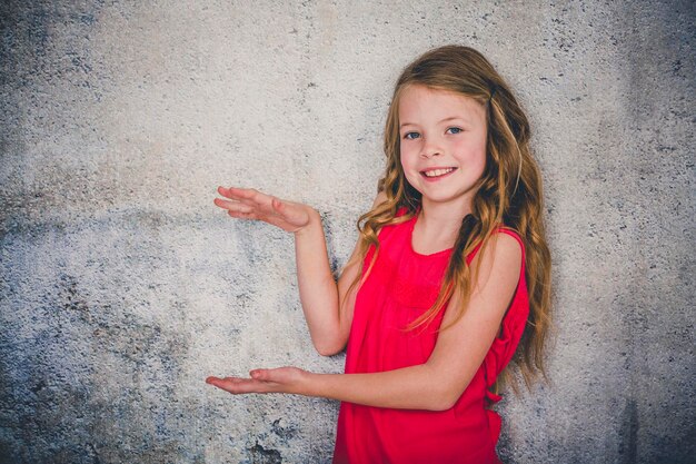 Foto ritratto di una ragazza sorridente in piedi contro il muro