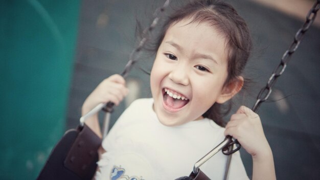 Portrait of smiling girl swinging in playground