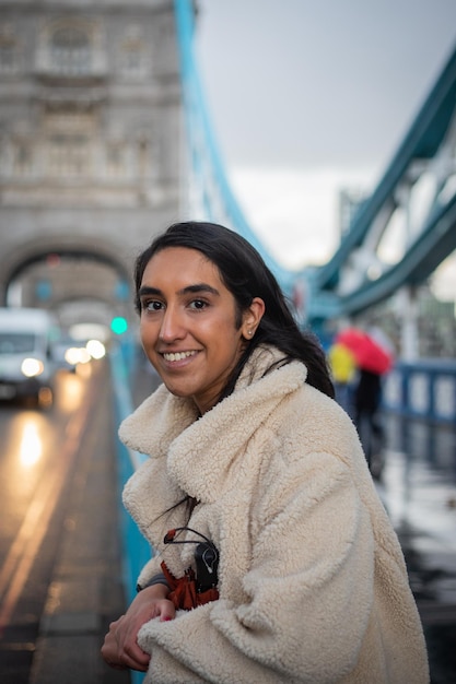 Портрет улыбающейся девушки, которая стоит в Лондоне на Тауэрском мосту