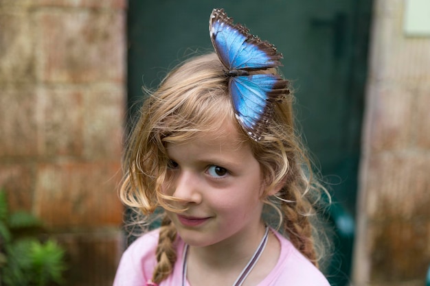 Photo portrait of smiling girl with butterfly on her head