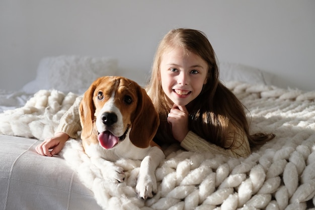 家のベッドに犬を連れて笑顔の女の子の肖像画