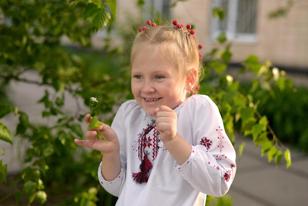 Portrait of a smiling girl with a flower in a Ukrainian embroidered shirt Kid's emotions from happy