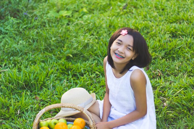 Portrait of smiling girl with fruit basket sitting on grass