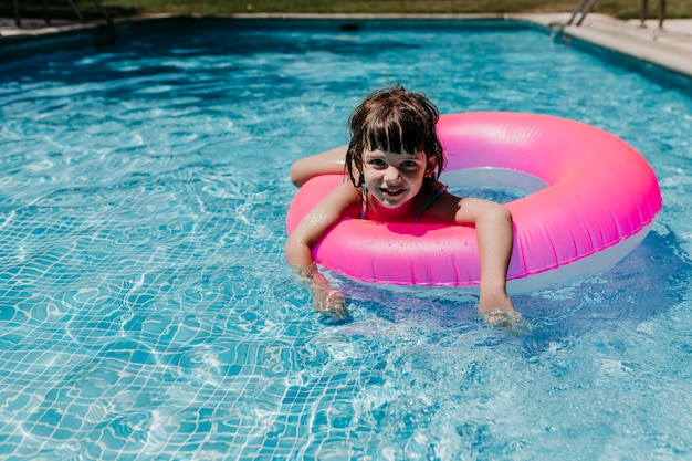 Photo portrait of smiling girl with inflatable ring in swimming pool