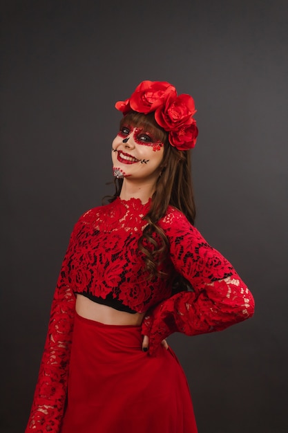 Portrait of a smiling girl with makeup and Dia de los Muertos outfit with gray background.