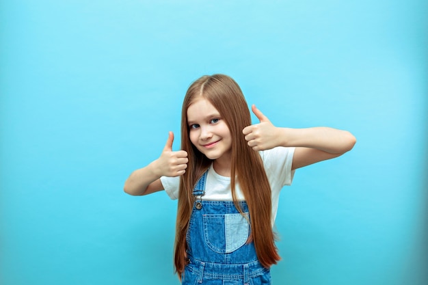 Photo portrait of a smiling girl with a raised thumb.