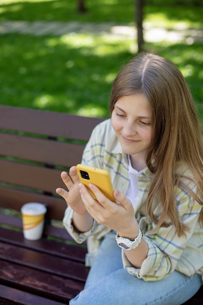 공원 벤치 개념 사람과 가제트에 그녀의 손에 스마트폰으로 웃는 소녀의 초상화