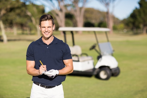 Portrait of smiling golfer writing on score card