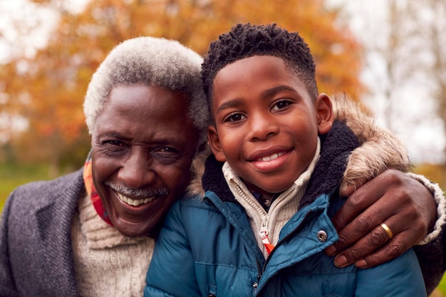 Portrait Of Smiling Grandfather And Grandson On Walk Through Autumn Countryside Together