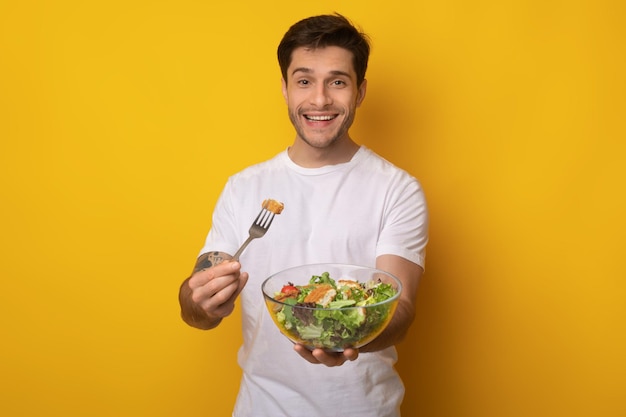 Photo portrait of smiling guy holding bowl with salad