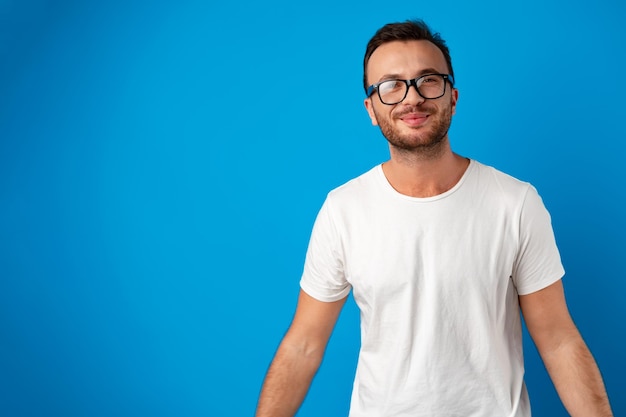 Portrait of smiling handsome guy in white tshirt over blue background