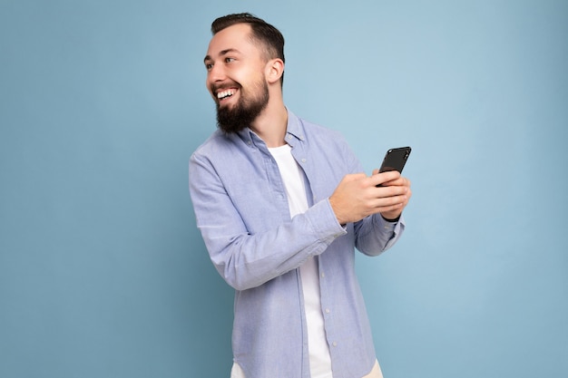 Ritratto di un bel giovane brunetta sorridente con la barba lunga con la barba che indossa una maglietta bianca alla moda e