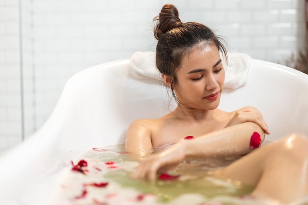 Портрет улыбающейся счастливой красавицы симпатичной азиатской женщины, чистой свежей здоровой белой кожи, расслабляющей, принимающей душ и ванну с пузырьковой пеной спа в ванне в ванной комнате