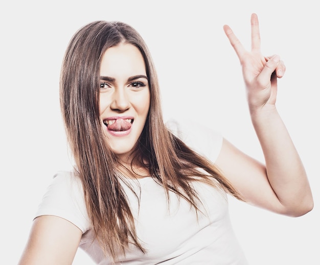 Portrait of a smiling happy woman showing victory sign and looking at camera