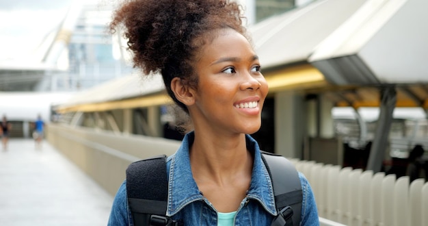 Portrait of smiling happy woman walking in street with backpack