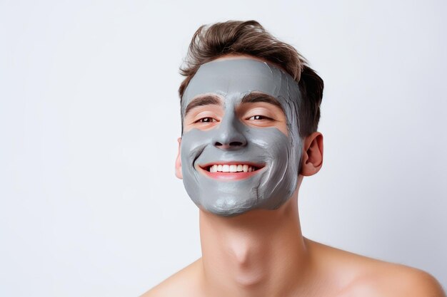 Portrait of a smiling happy young man smiling while pampering his skin with a face mask