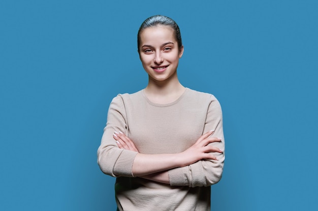 Foto ritratto di una studentessa alle superiori sorridente su sfondo blu