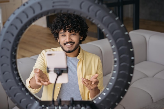 Portrait of smiling Indian blogger influencer recording video sitting at home