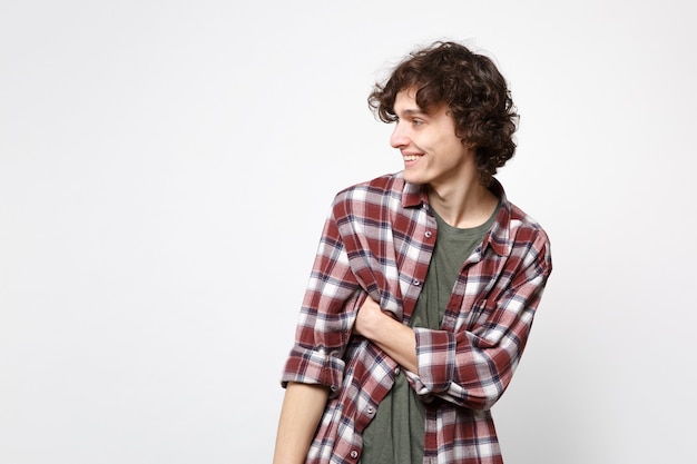 Portrait of smiling joyful handsome young man in casual clothes standing and looking aside isolated on white wall background in studio. People sincere emotions, lifestyle concept. Mock up copy space.