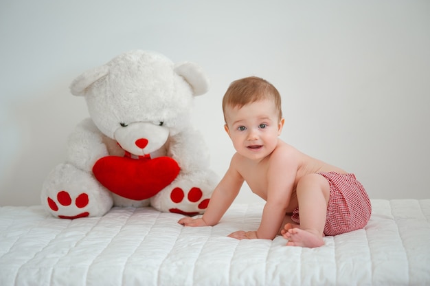 Portrait of a smiling kid with a toy bear on a light background