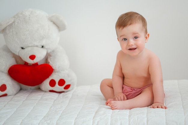 Foto ritratto di un bambino sorridente con un orso giocattolo su uno sfondo chiaro