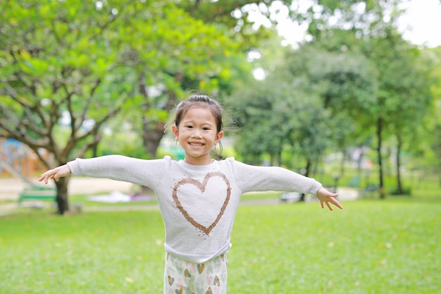 Portrait of smiling little Asian children opened her hands in the green garden.