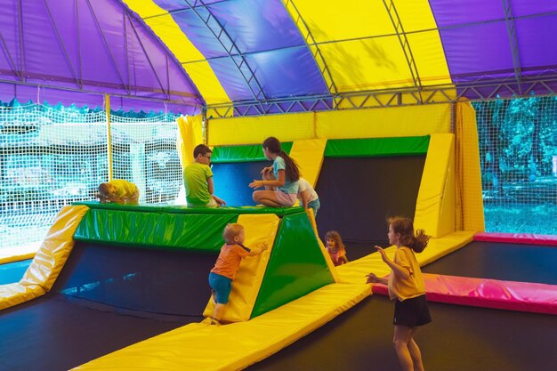 Photo portrait of the smiling little boy who is jumping in the trampoline park outdoors