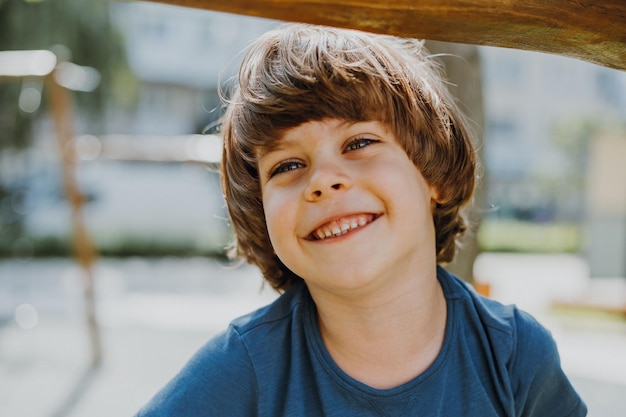 Portrait of a smiling little brunette boy in a blue T-shirt playing outdoors. happy child, lifestyle. products for children. High quality photo