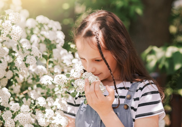 Portrait of a smiling little girl near a flowering tree with white flowers