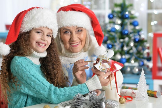 Portrait of smiling little girl with grandmother preparing for Christmas