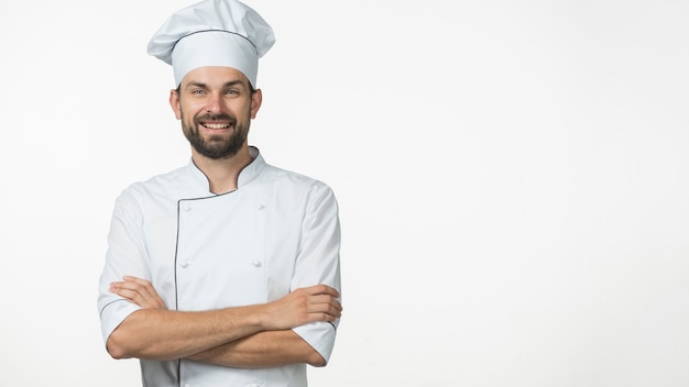 Foto ritratto del cuoco unico maschio sorridente in uniforme di bianco isolata sopra priorità bassa bianca