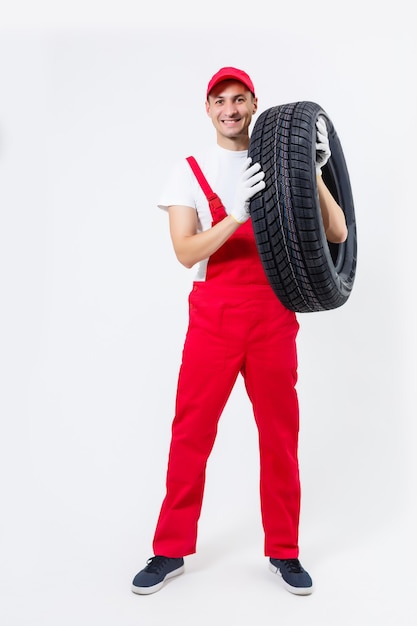 Portrait of smiling male mechanic holding tire on white background