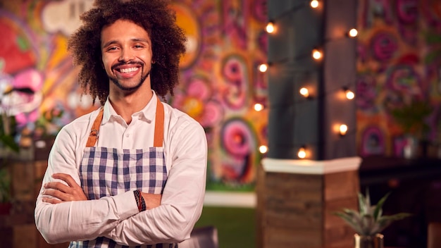 Portrait of smiling male server working night shift in bar\
restaurant or club