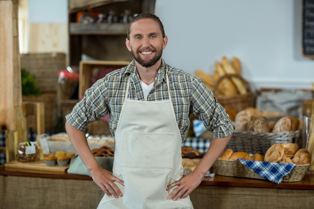 Portrait of smiling male staff standing with hands on hip