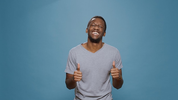 Portrait of smiling man celebrating success and achievement, feeling happy standing over blue background. Cheerful adult enjopying big win and victory, satisfaction cheers goal.