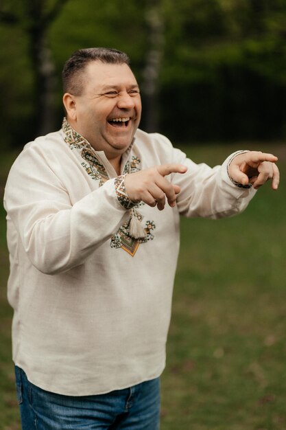 Portrait of a smiling man in an embroidered shirt on a background of the park