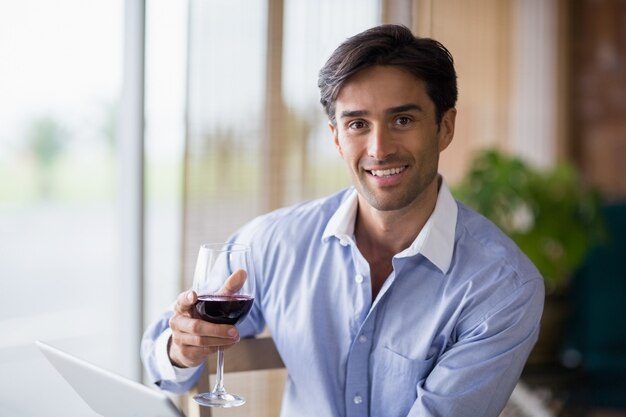 Ritratto dell'uomo sorridente che tiene vetro di vino rosso