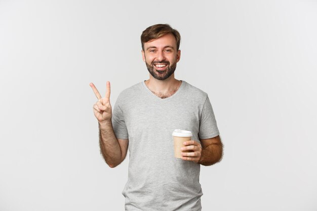 Portrait of smiling man holding ice cream against white background