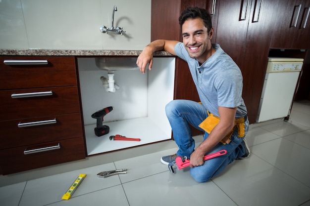 Portrait of smiling man holding pipe wrench 