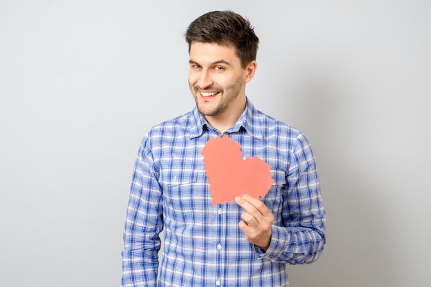 Portrait of smiling man holding red paper pixel heart