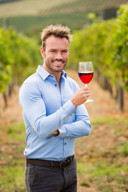Ritratto dell'uomo sorridente che tiene bicchiere di vino rosso
