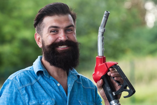 Portrait of a smiling man refueling car at the gas station Man on petrol pump filling nozzles Gas station Portrait of bearded man hold fueling nozzle gasoline fuel pump