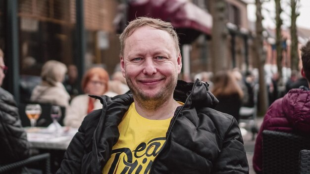 Photo portrait of smiling man sitting at outdoor cafe