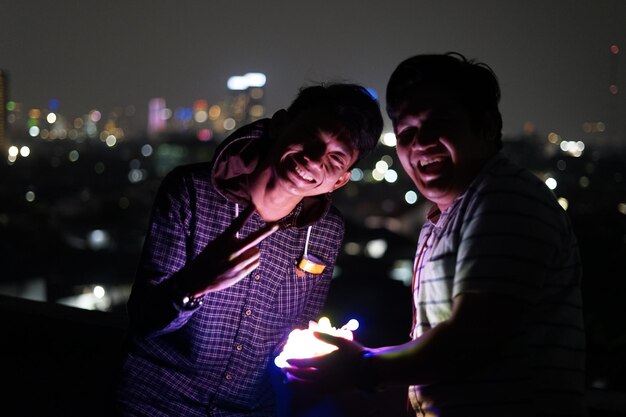 Portrait of smiling man standing with friend at night