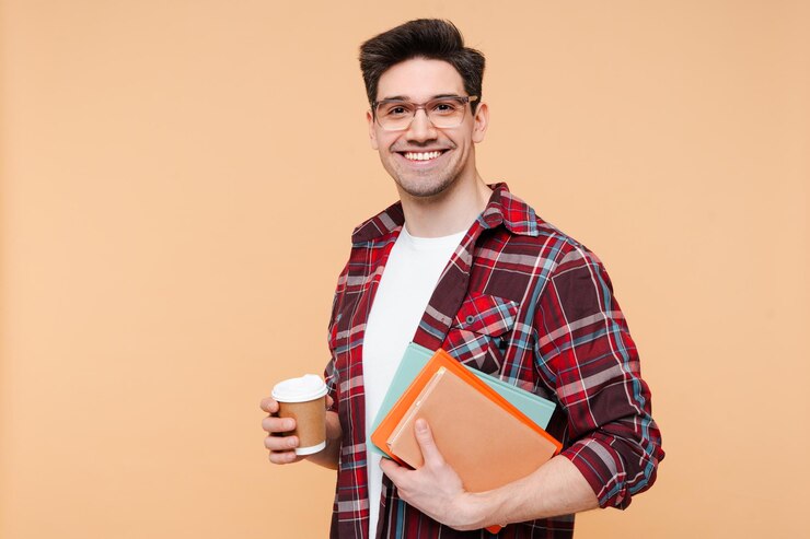 Photo portrait of smiling man student holding coffee and books looking at camera