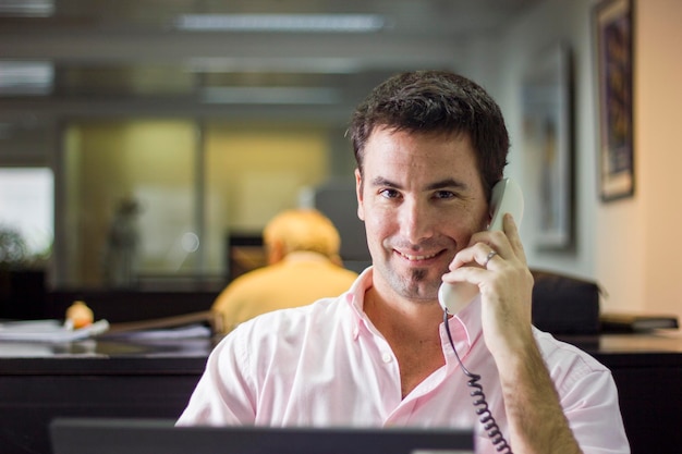 Foto ritratto di un uomo sorridente che parla al telefono in ufficio