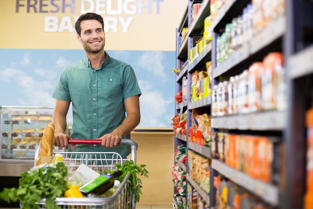 Portrait of smiling man walking in aisle with his trollet 